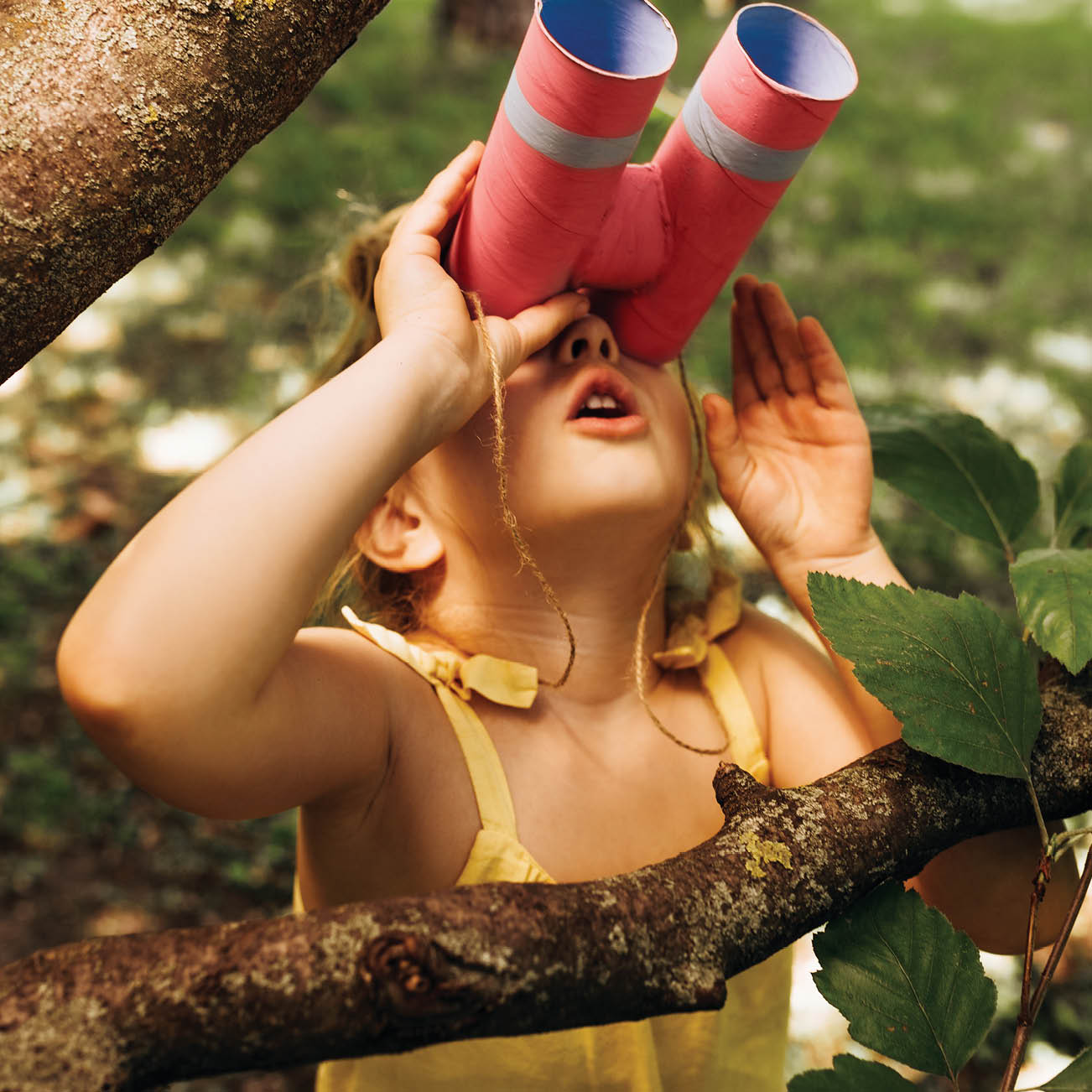 young girl in a tree using binoculars