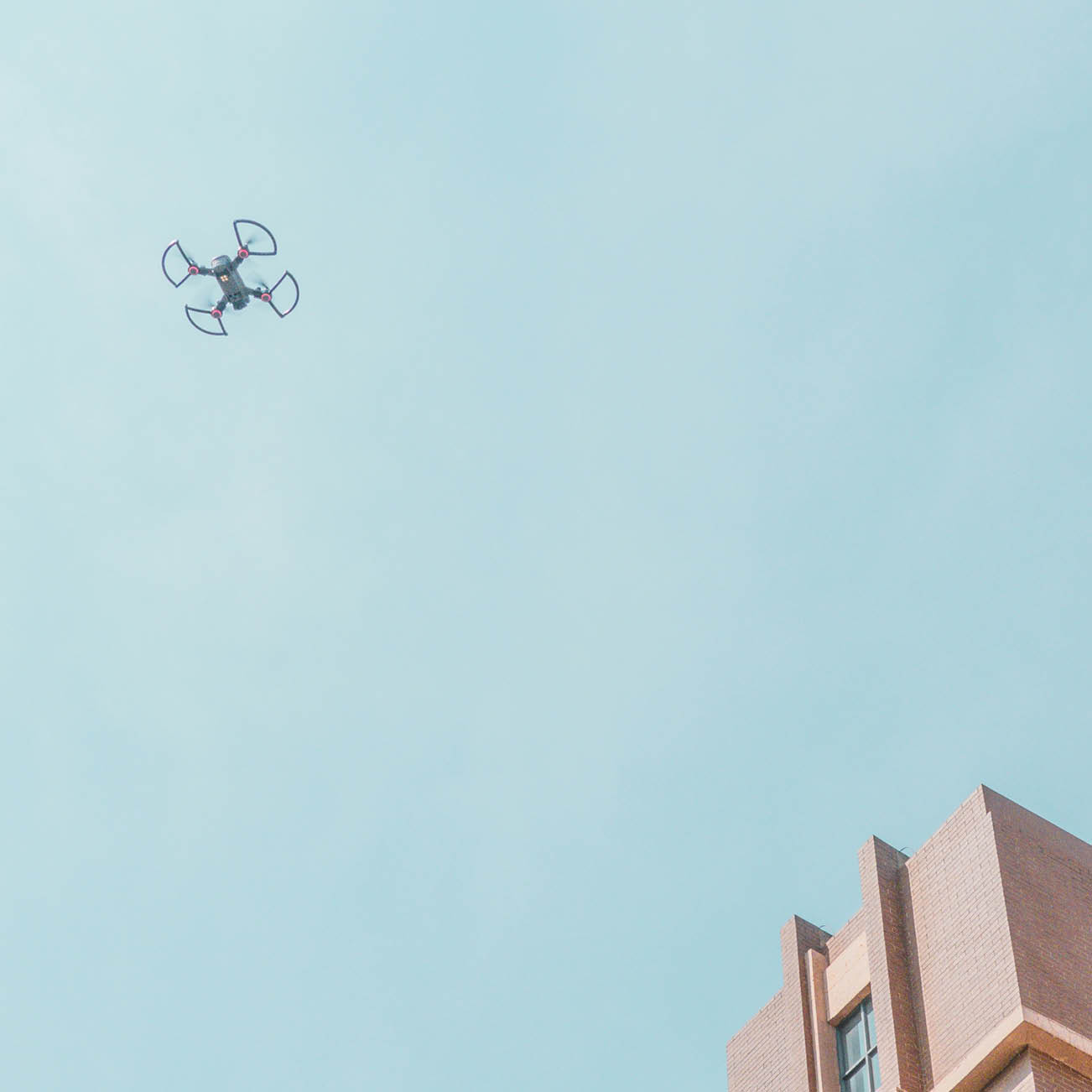 drone flying high in the sky above building