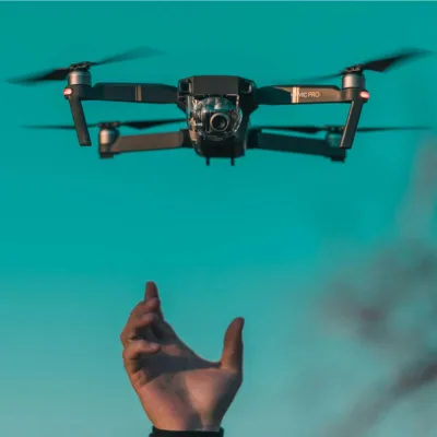 hand reaching upward toward drone taking flight