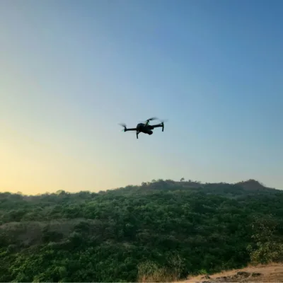 drone flying high in the sky over trees