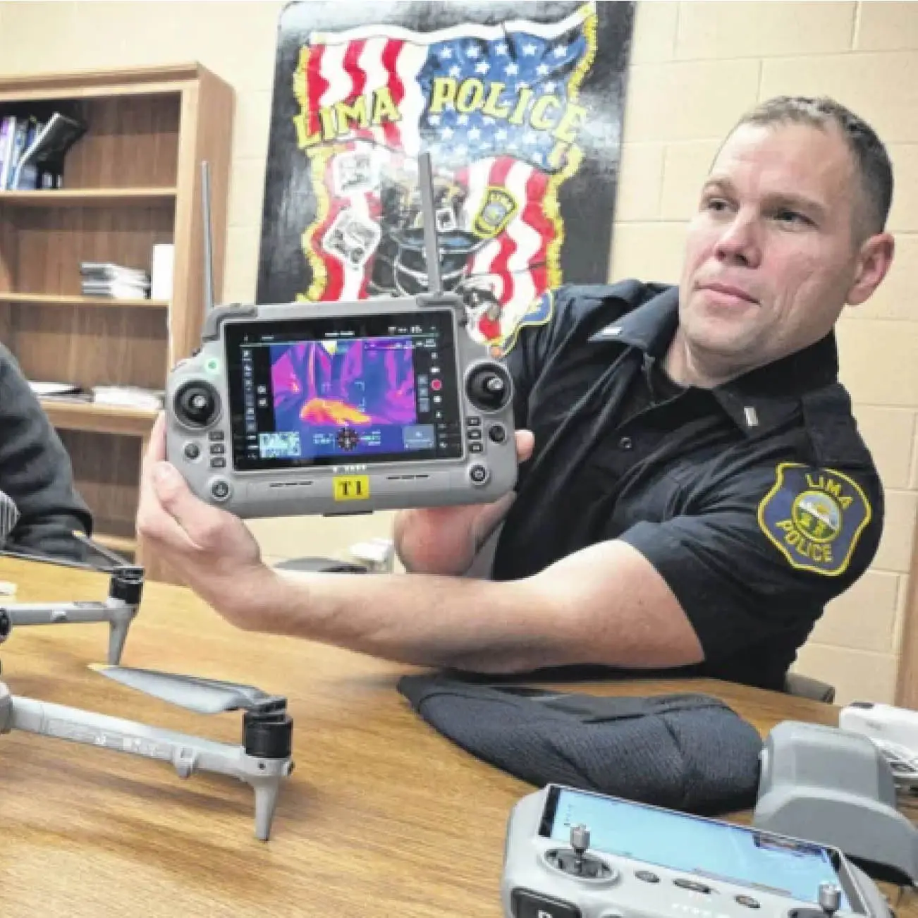 Lima Police Department Lt. Ben Thompson, right, demonstrates how a drone can use thermal imaging to identify where Lt. Matt Douglass was on Dec. 5. The department credits drone flights with helping solve some recent crimes and helping keep officers safe at crime scenes.